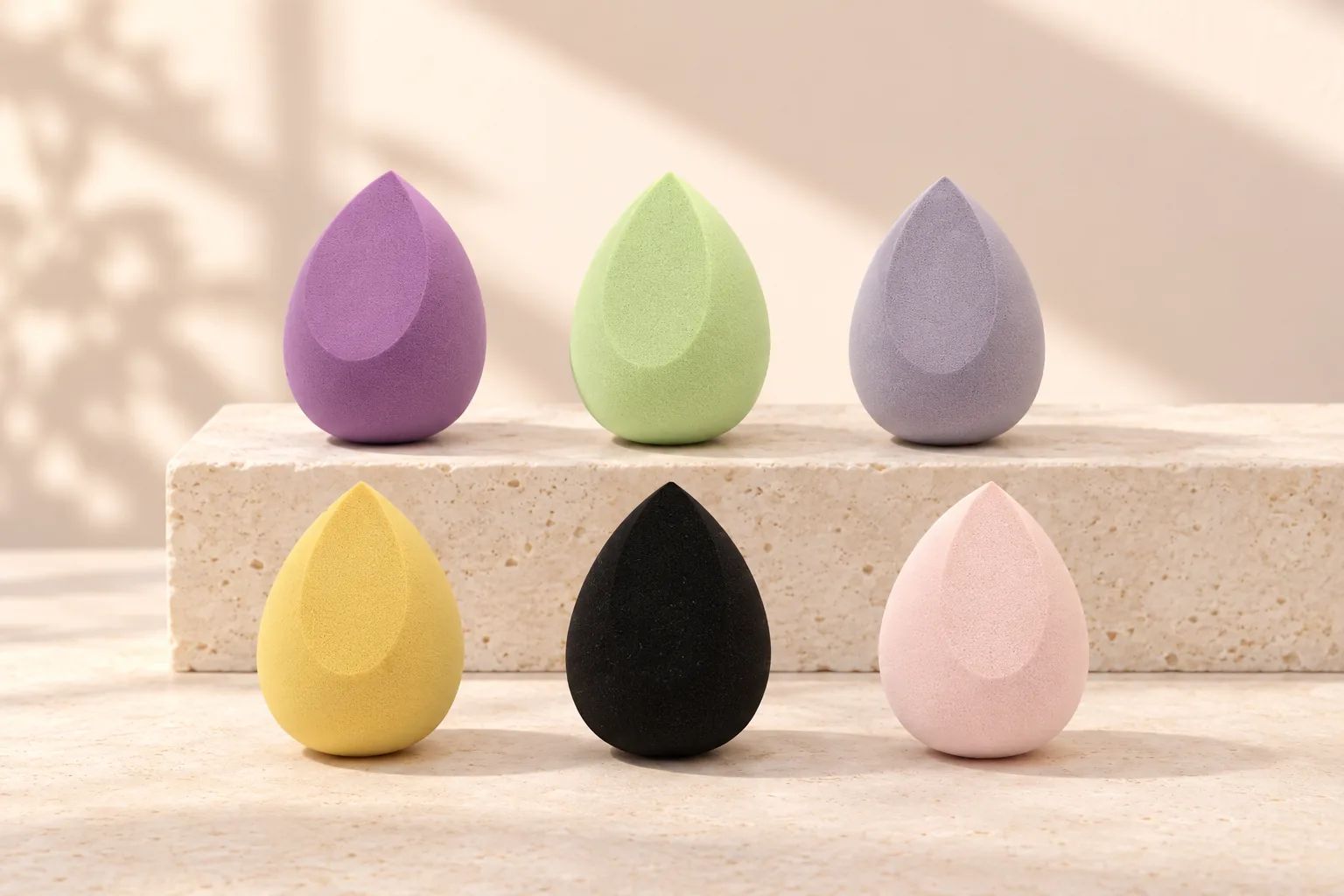 Six real GAMBUR makeup sponge color variants in a refined studio scene