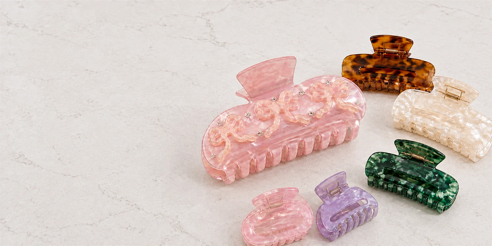 Six original hair claw clips on a neutral stone vanity counter