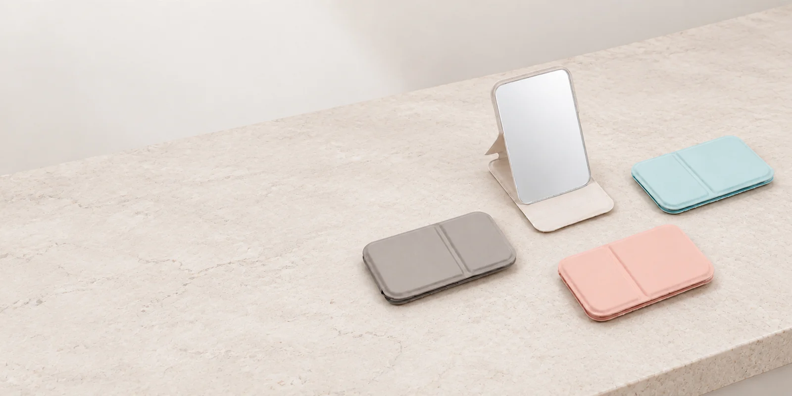 Four original folding makeup mirrors on a neutral stone vanity counter